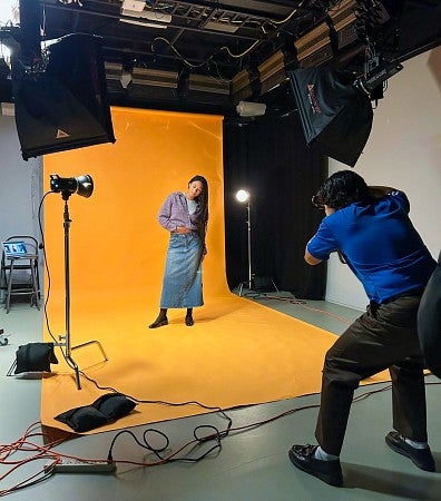 Charlie Nguyen shoots photos of a fellow student model in the Allen Hall studio